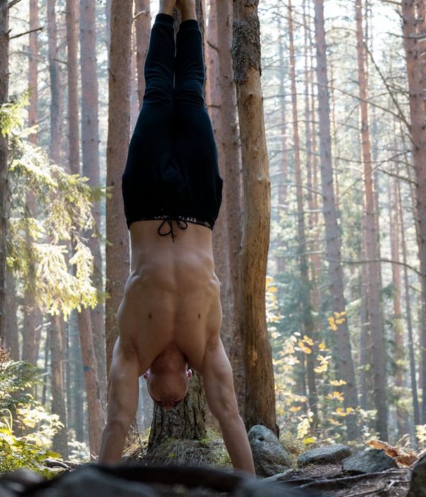 Man performing a controlled bodyweight exercise with intense focus in a dark setting.